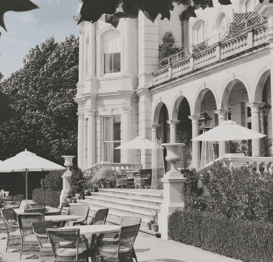 Classical estate with arched colonnades, stone steps, and a garden terrace